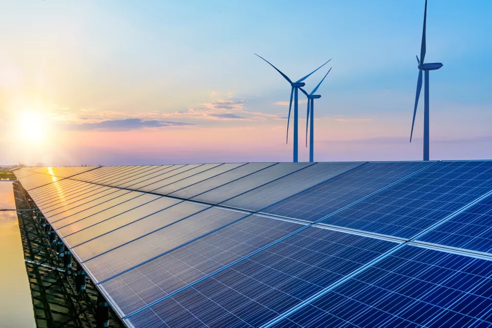 Solar panels and wind turbines against sunset colors